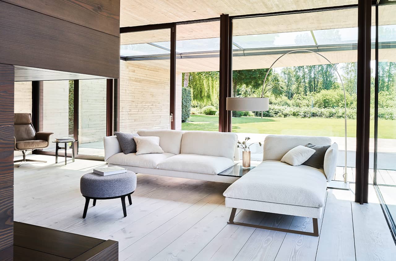 Großzügiges Sofa in hellem Bezug, das mit seiner offenen Form und weichen Polsterung ein entspanntes Wohngefühl vermittelt.